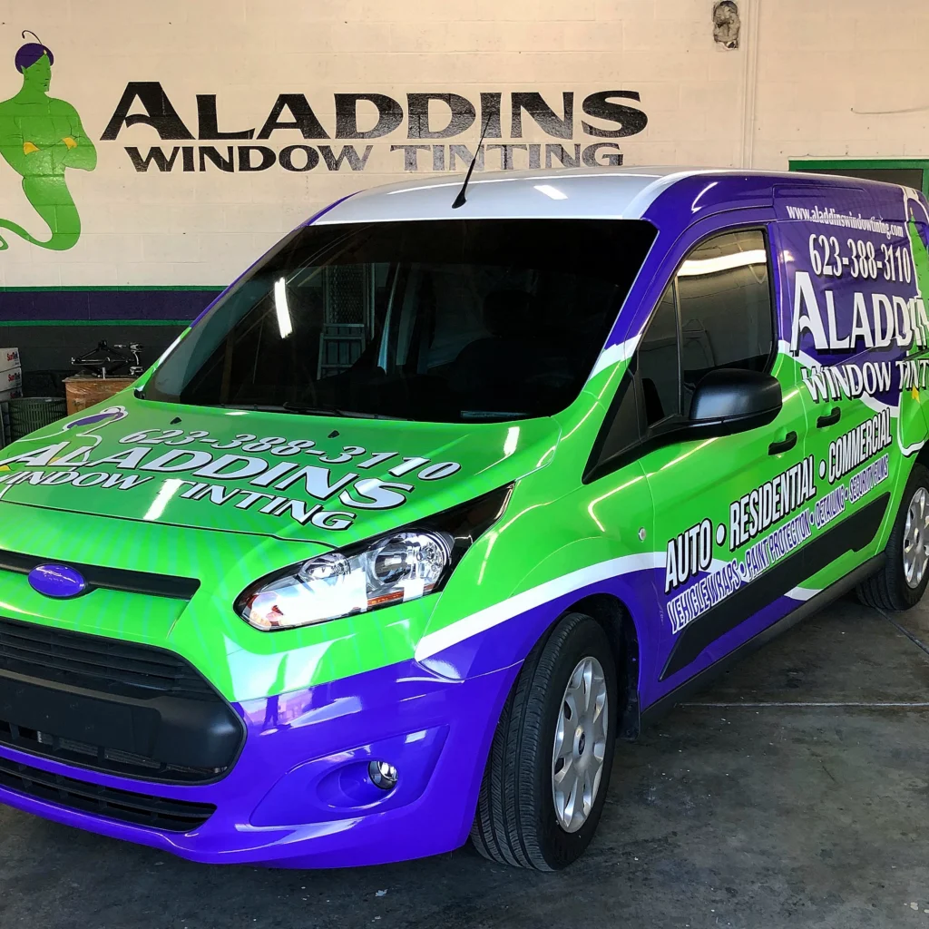 Aladdins Window Tinting company van with a completed green and purple vinyl wrap, parked inside the shop.