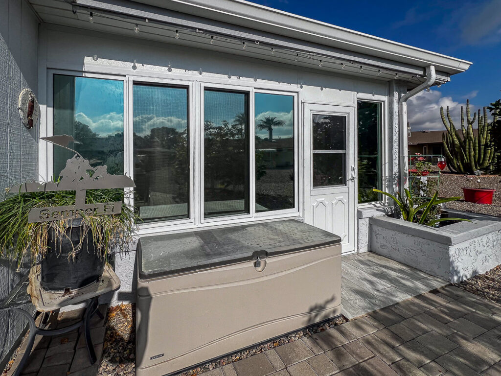 Exterior of an Arizona room in Sun City with reflective tinted windows beside a backyard patio.