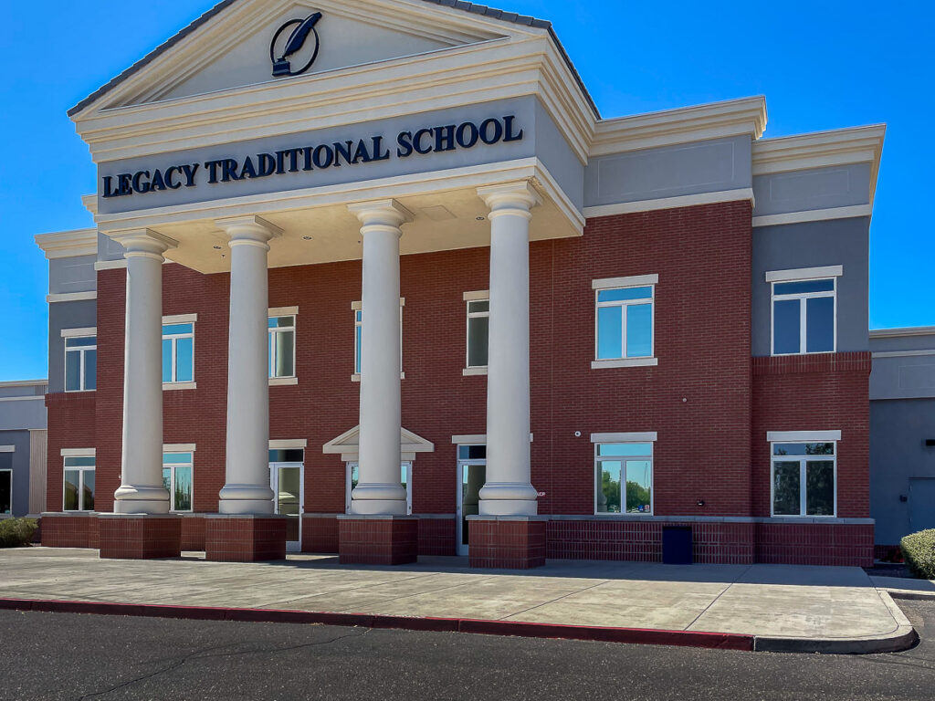 Legacy Traditional School in Surprise with tinted windows, a red brick exterior, and tall white entrance columns.