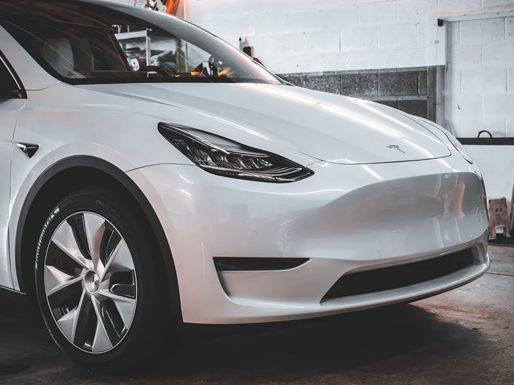 Front three-quarter view of SunTek Ultra installed on a white Tesla Model Y inside the Aladdins Window Tinting shop.