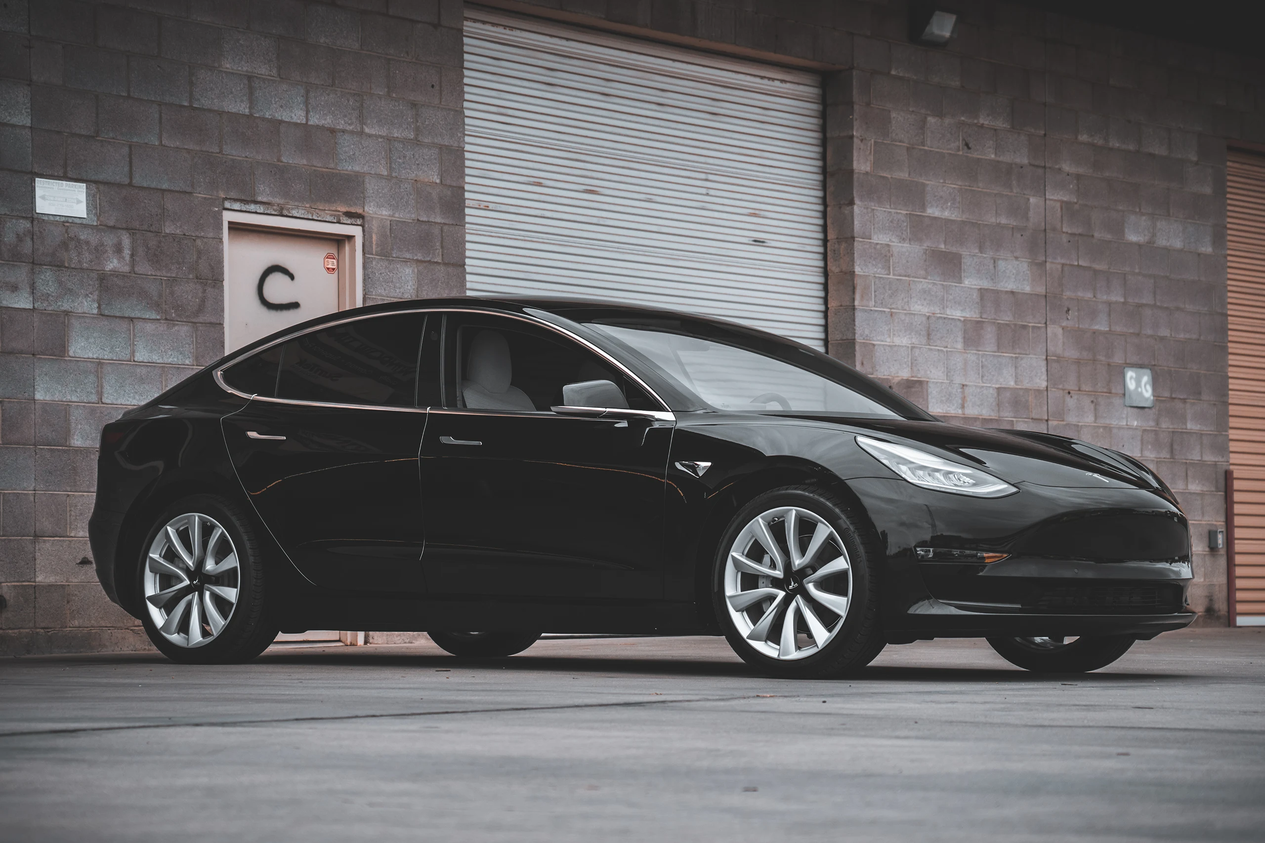 Black Tesla Model 3 with tinted windows outside Aladdins Window Tinting in Peoria, Arizona